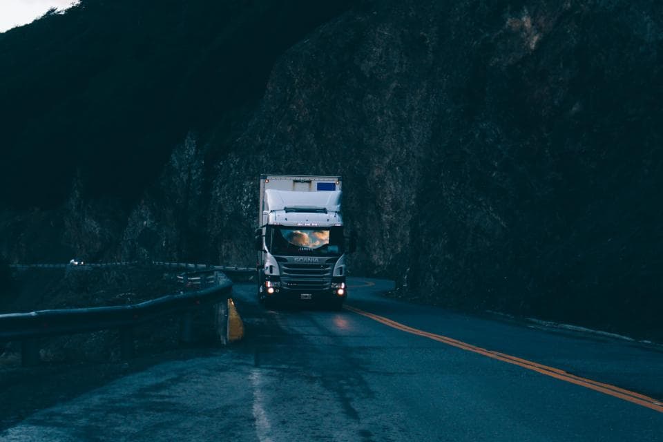 Delivery truck with headlights on driving along a mountain road